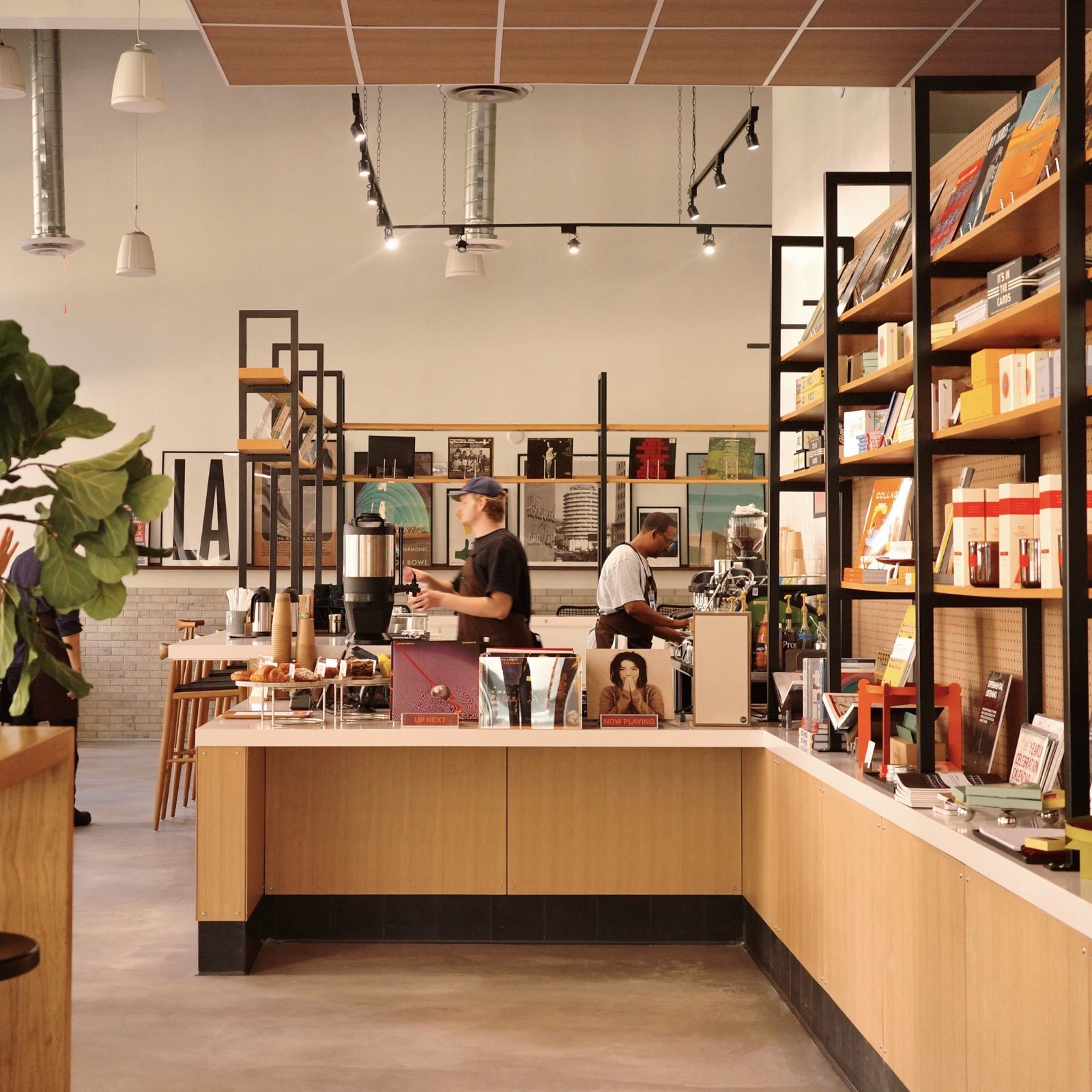 Inside Demo Café: a pale wood counter with baristas at work, shelves of books and records along the wall.