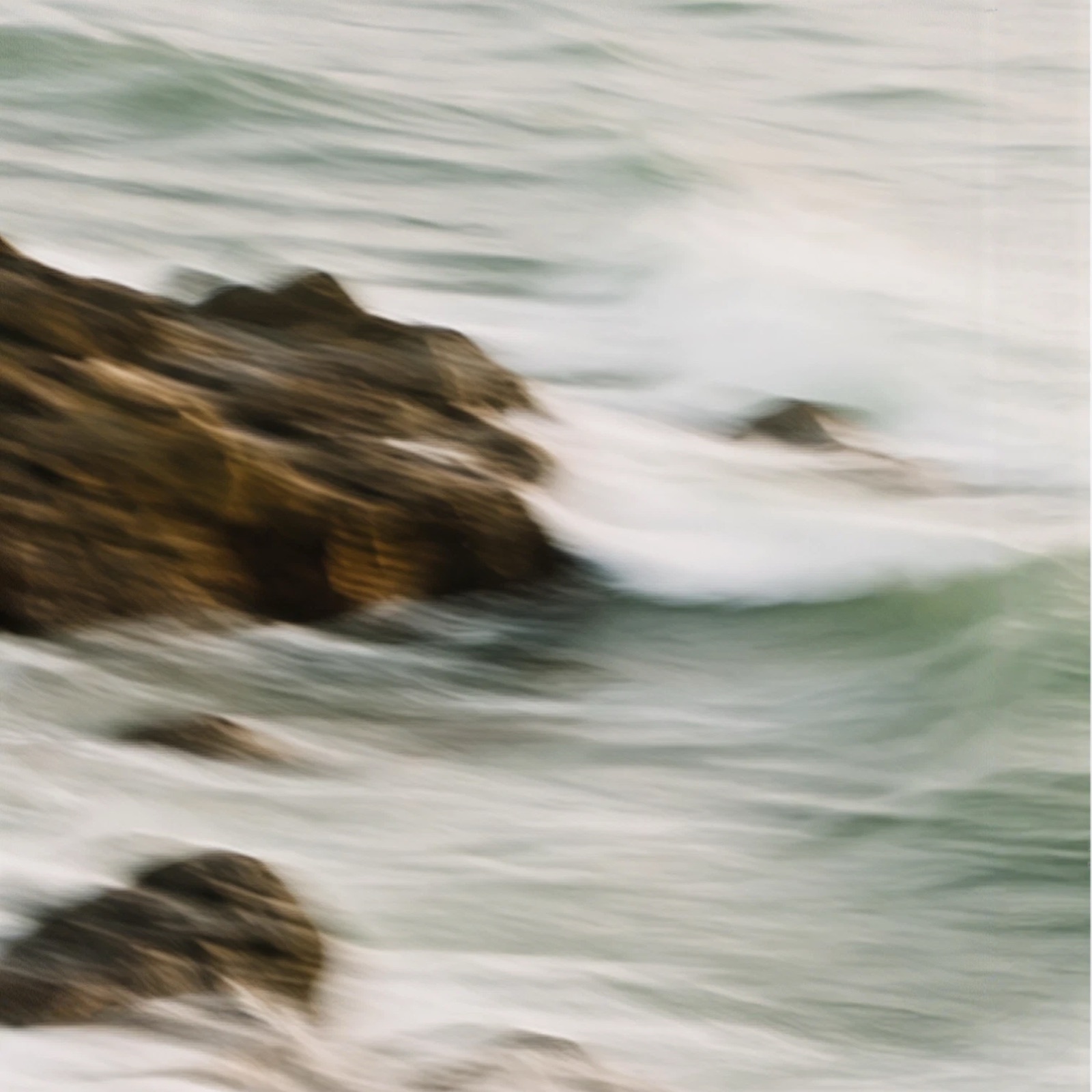 Waves breaking over rocks, blurred by a long exposure.